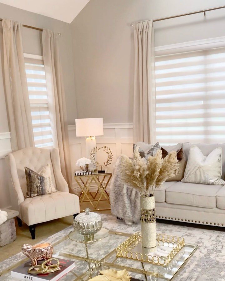 Beige curtains and zebra blinds on windows in a neutral toned living room