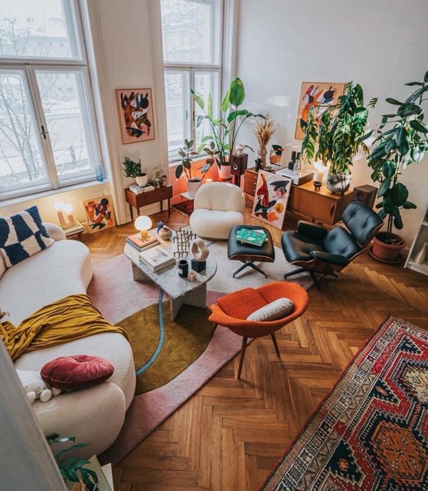 Bright living room with a bold orange accent chair and eclectic mid-century furniture.