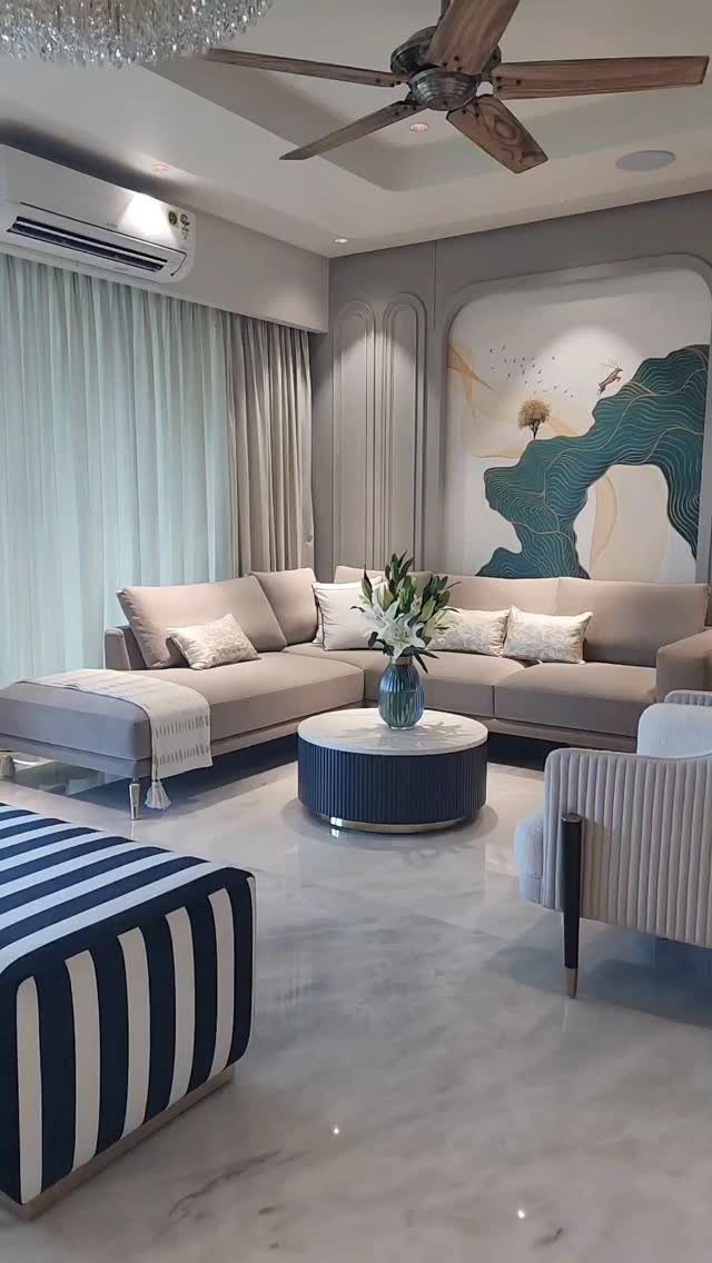 Modern living room featuring a grey sectional sofa and a blue striped ottoman.