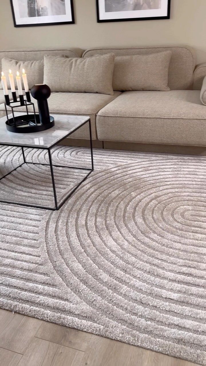 Large grey circular patterned rug in a living room with beige sofa.