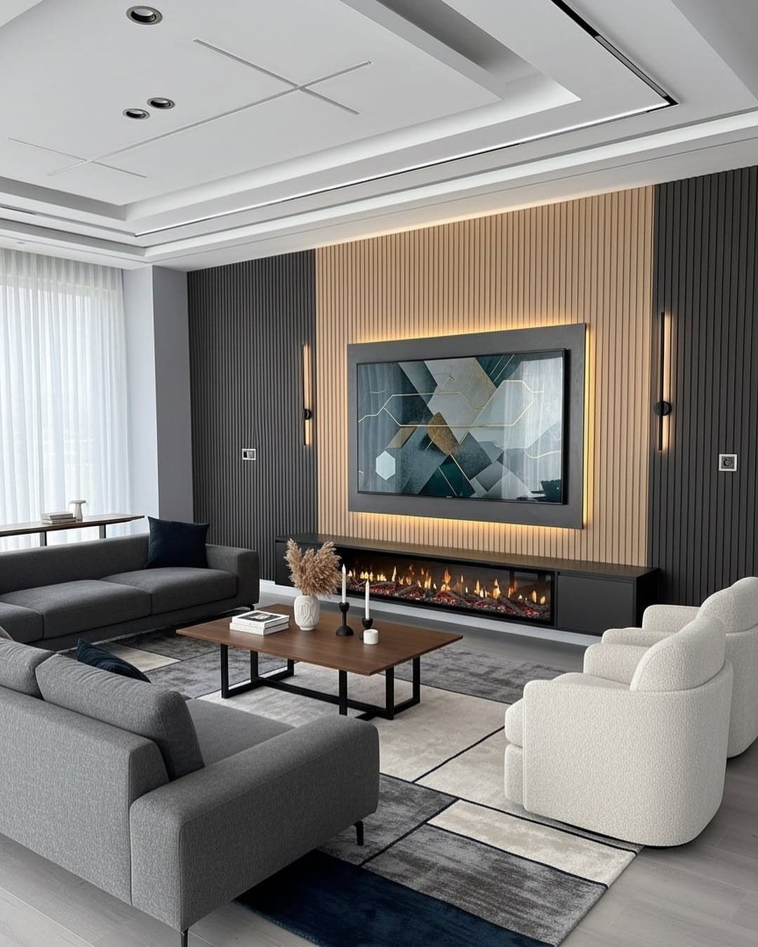 Modern living room with grey sofas, white armchairs, and a geometric area rug.