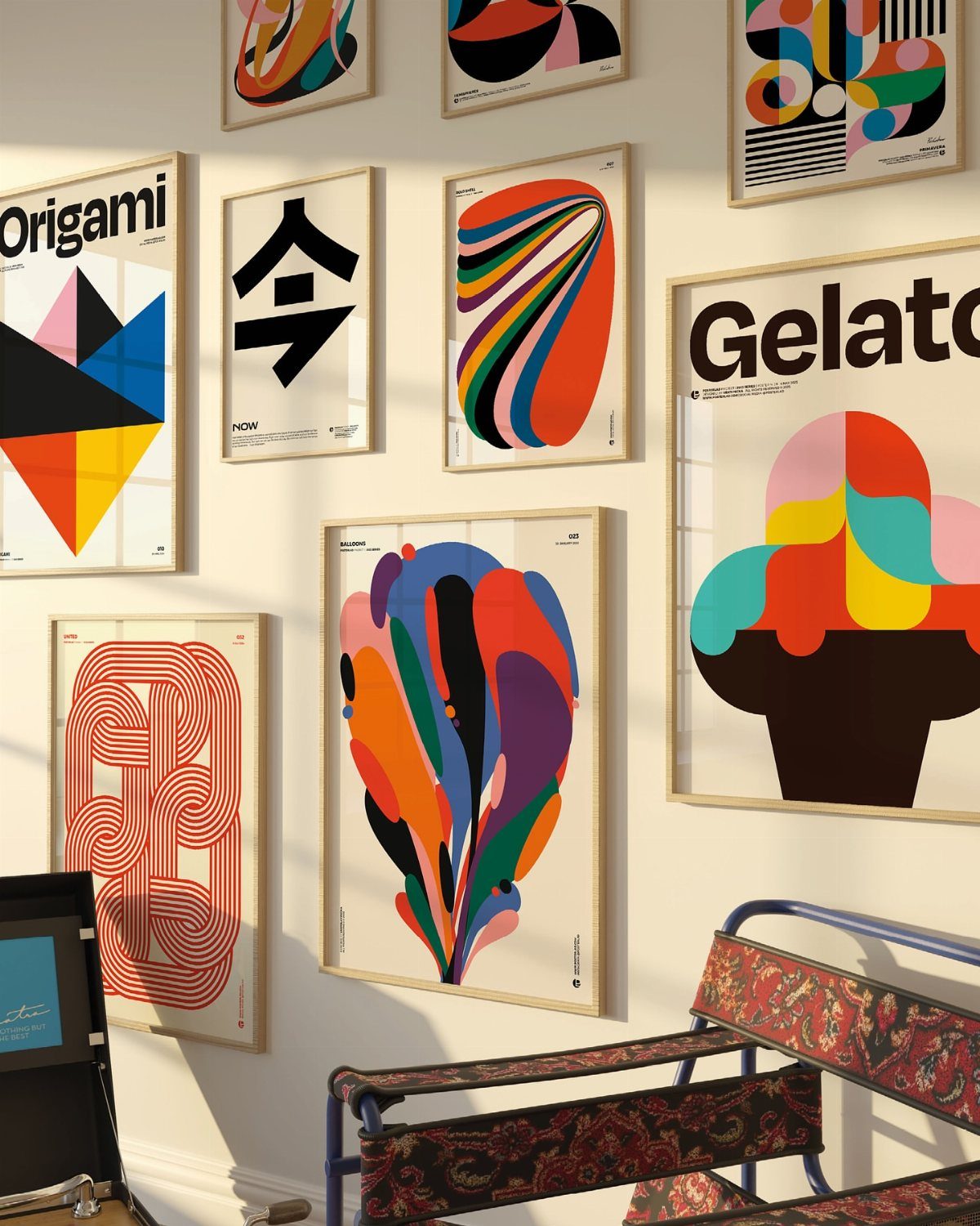 Framed bold abstract art prints hanging on a white wall above a chair.