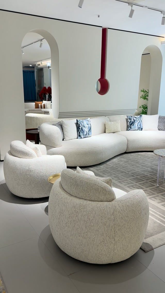 Curved white sectional sofa and rounded accent chairs in a bright modern living room