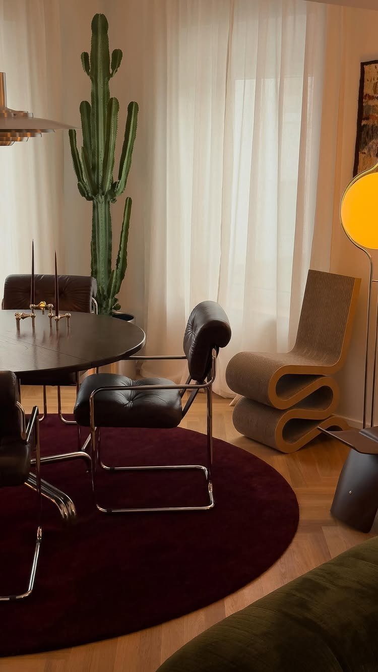 Mid-century modern room with black leather chairs, burgundy rug, and a tall cactus.