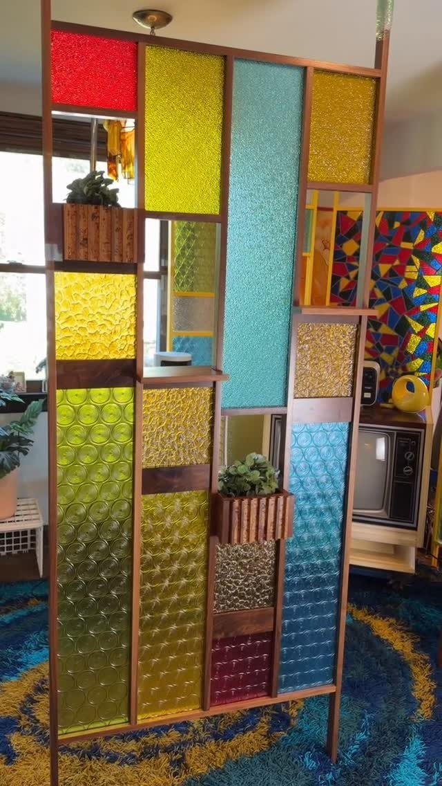 Colorful midcentury modern glass room divider with wooden planters and shag rug.