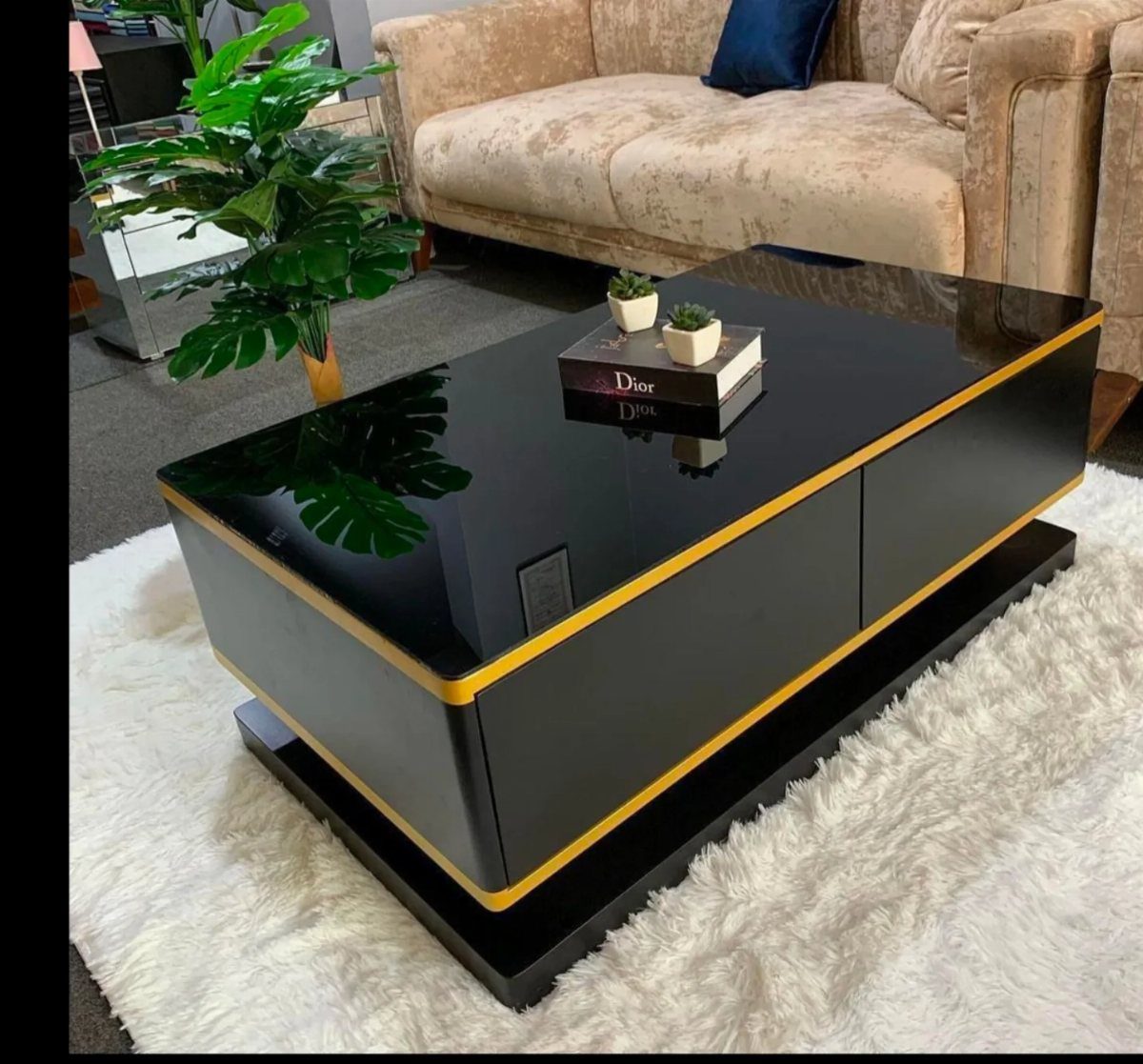 Black glossy coffee table with gold trim on a white shag rug.