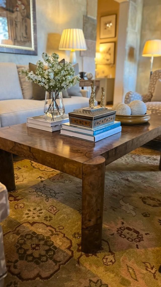 Burl wood coffee table with books and white flowers in a living room