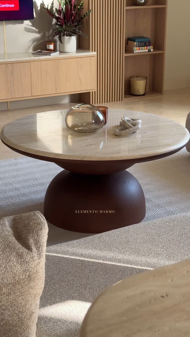 Round white marble coffee table with a dark brown base and glass bowl centerpiece.