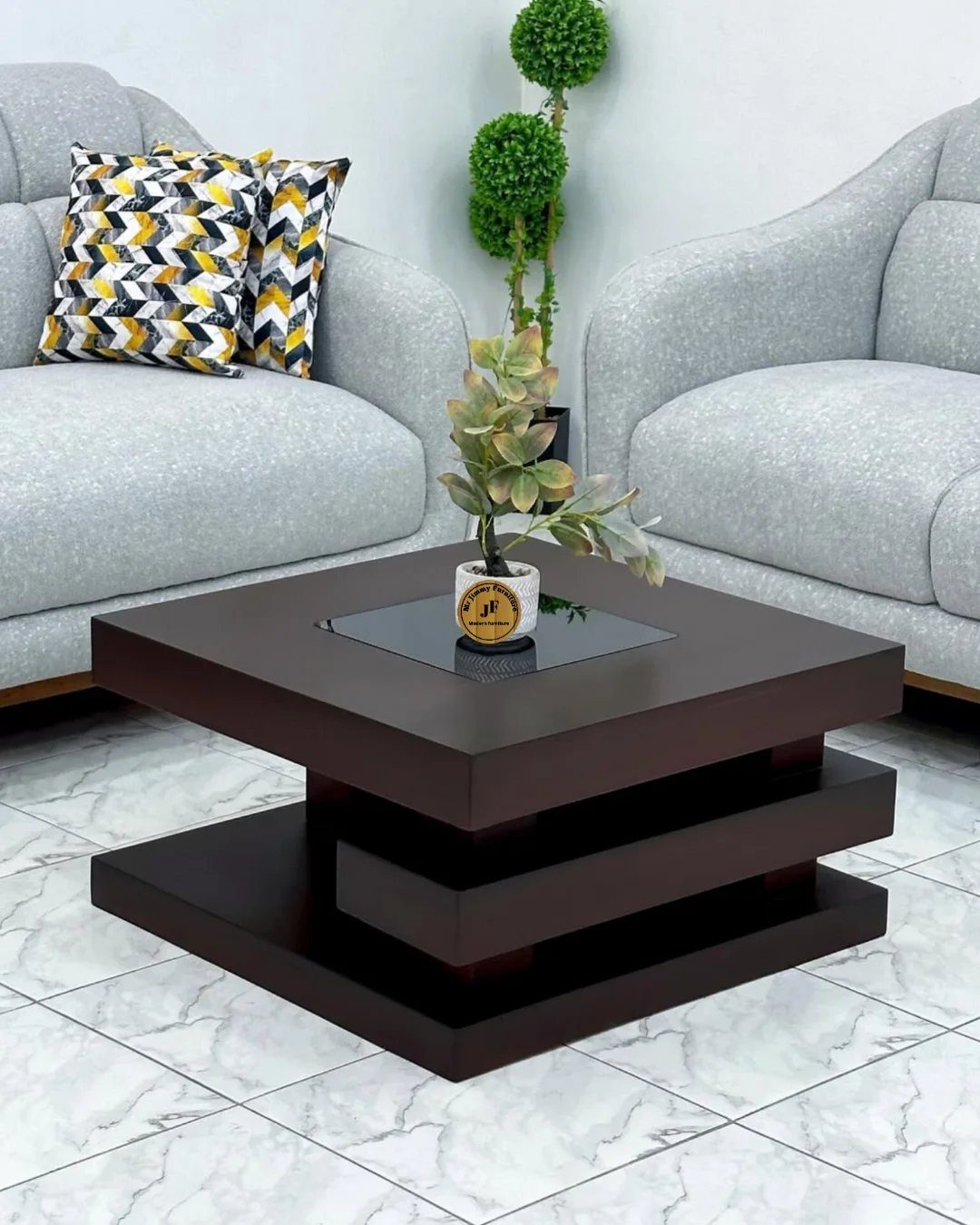 Dark brown tiered square coffee table with a small plant on a glass inset.