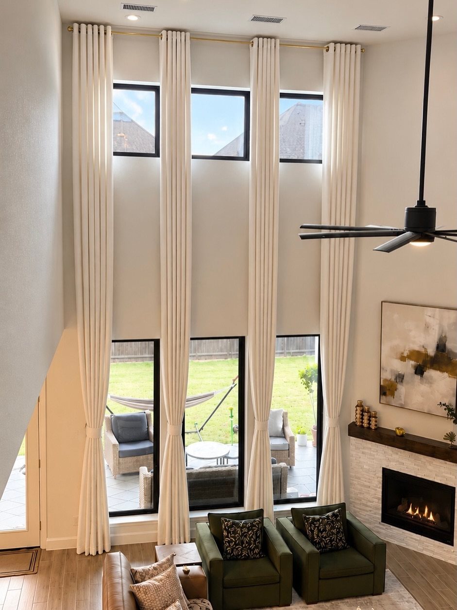 White floor-to-ceiling drapes framing large windows in a modern farmhouse living room.