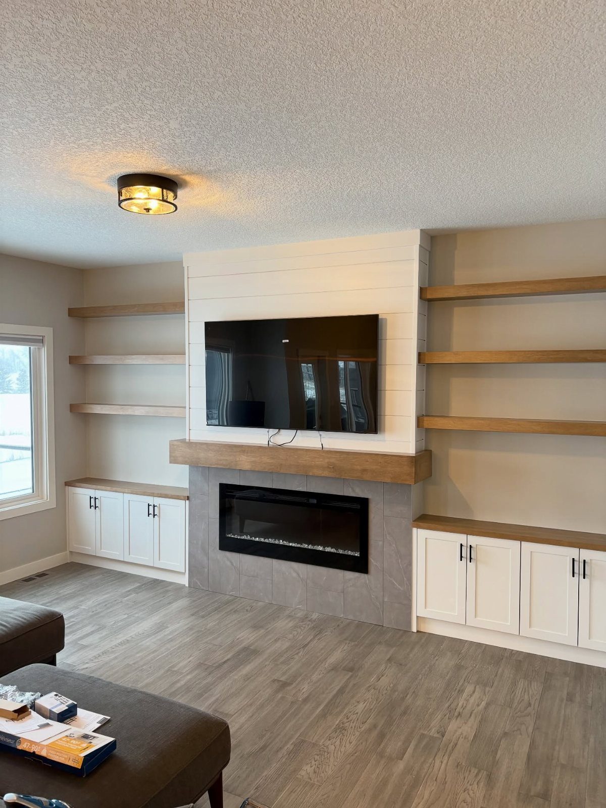 Modern farmhouse living room with shiplap wall, electric fireplace, and floating wooden shelves.