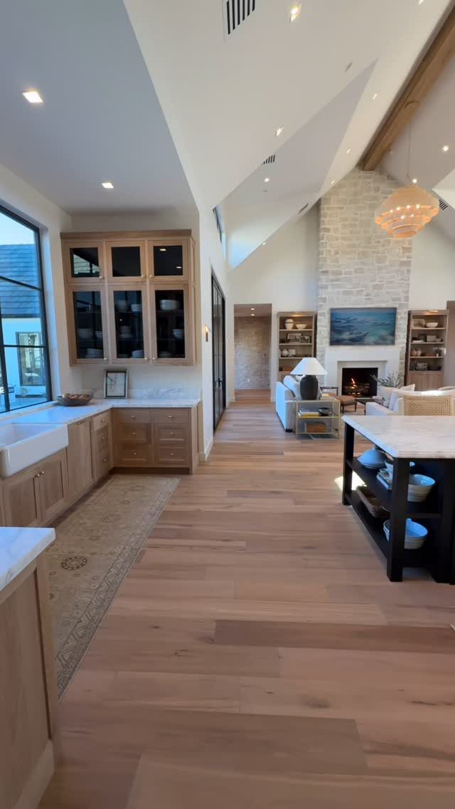 Light-toned wood floors extending from a kitchen into a modern farmhouse living room.