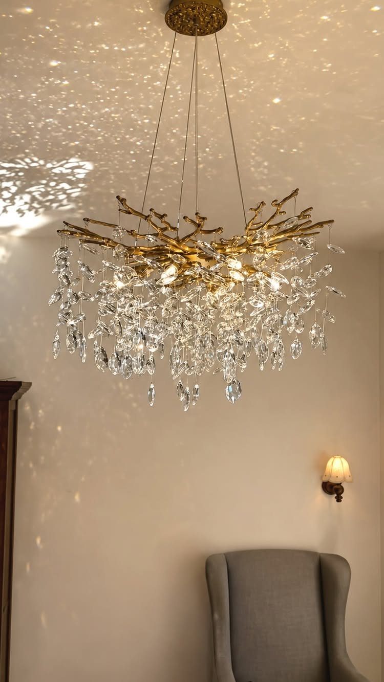 Gold branch chandelier with hanging crystals illuminating a neutral living room interior