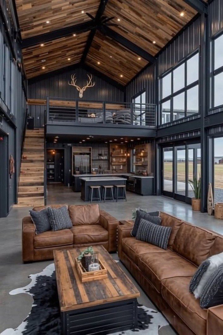 Modern rustic living room with leather sofas, wooden ceiling, and black industrial walls.