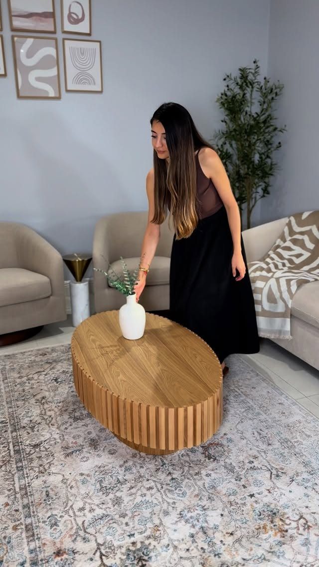 Oval fluted wooden coffee table in a modern living room with neutral furniture.