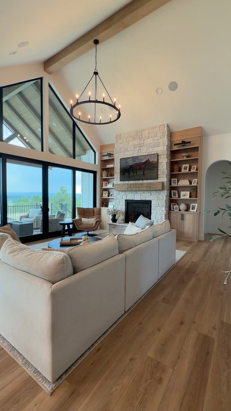 Large black-framed windows in a rustic living room with a stone fireplace.