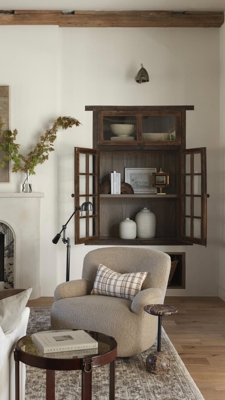 Dark wood wall cabinet and beige bouclé armchair in a modern rustic living room