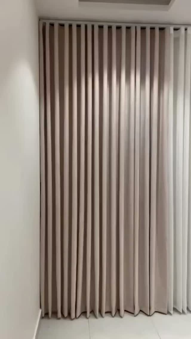 Beige floor-to-ceiling curtains with ripple folds skimming a light tiled floor.