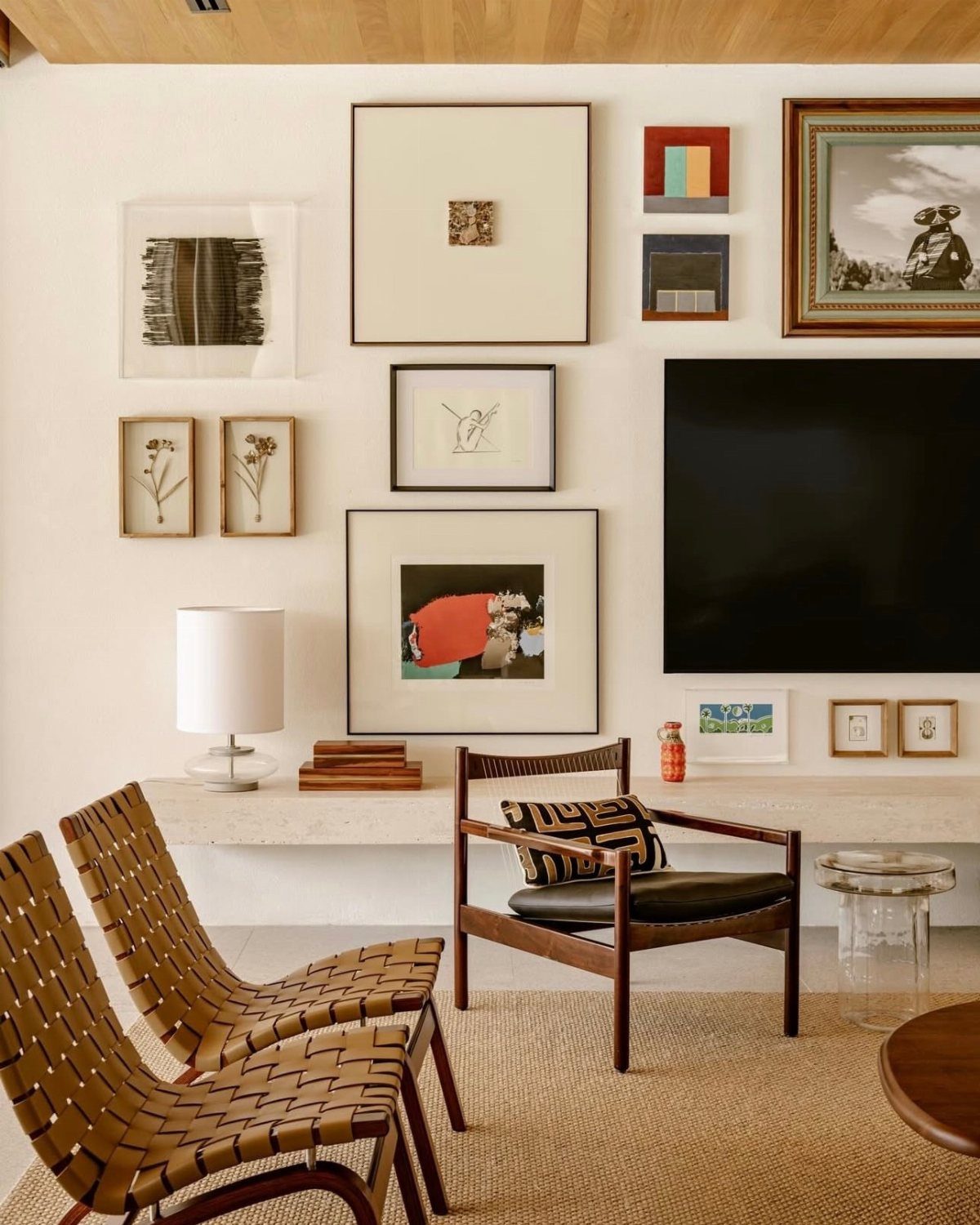Gallery wall with various framed art pieces above a modern living room seating area