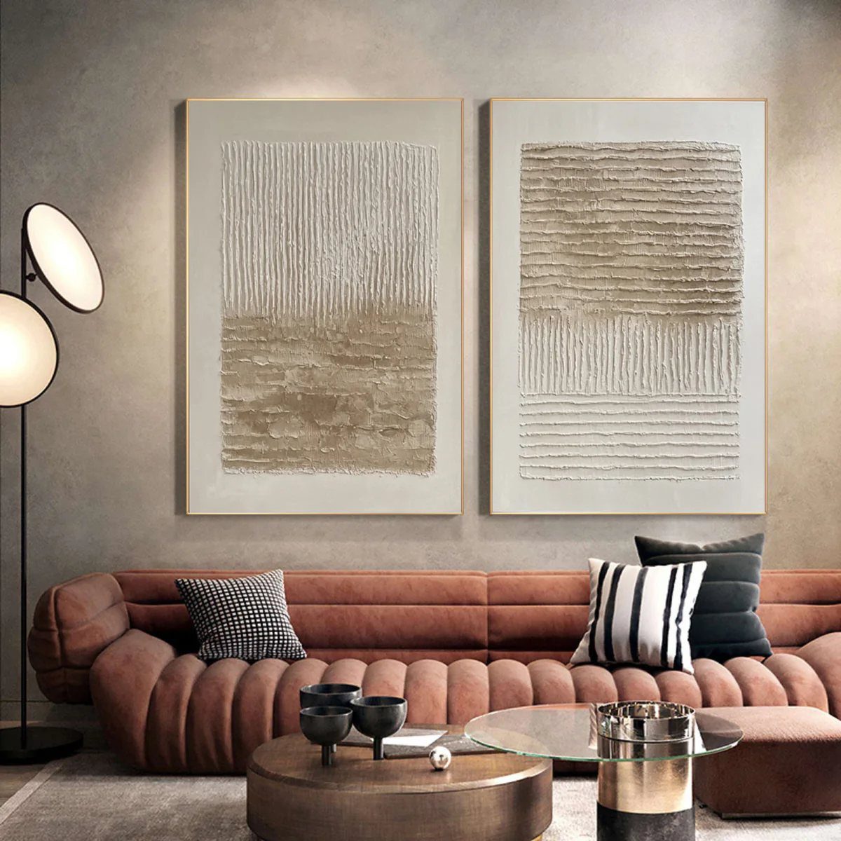 Two large textured abstract paintings hanging above a brown ribbed leather sofa.