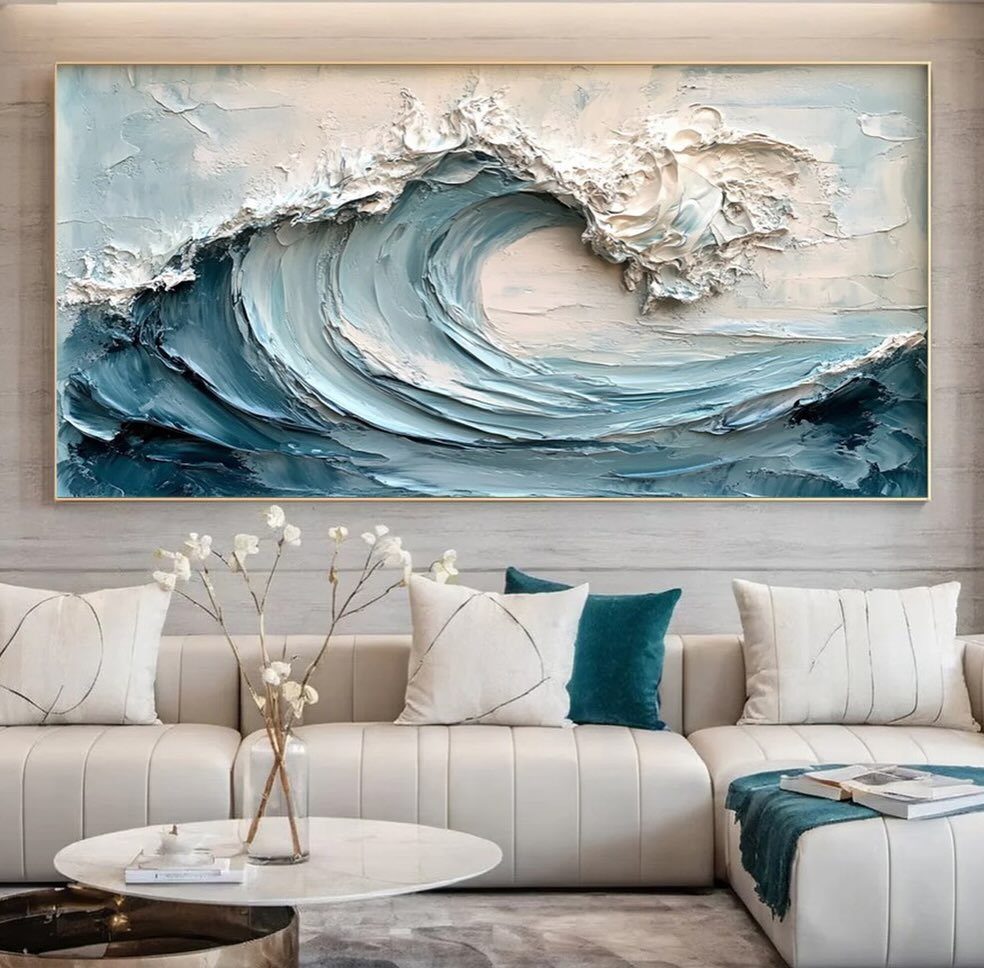 White ribbed sofa and marble table under a large textured ocean wave painting.