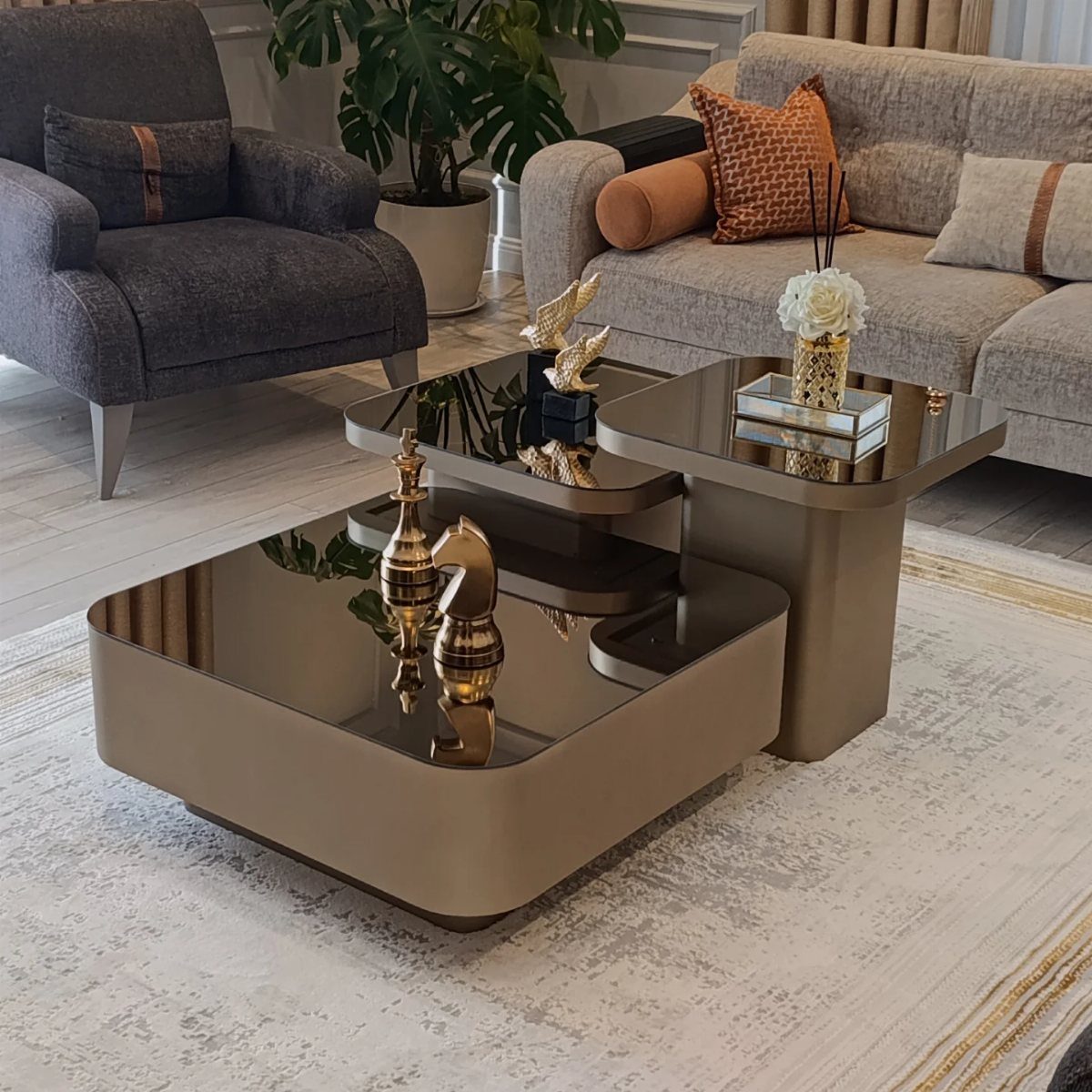 Gold metallic tiered coffee tables with reflective tops in a modern living room