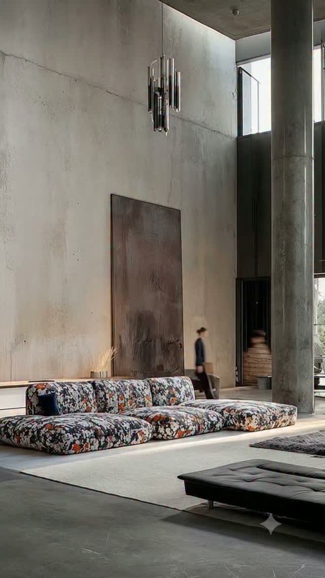 Floral patterned modular sofa in a modern room with concrete walls and high ceilings.