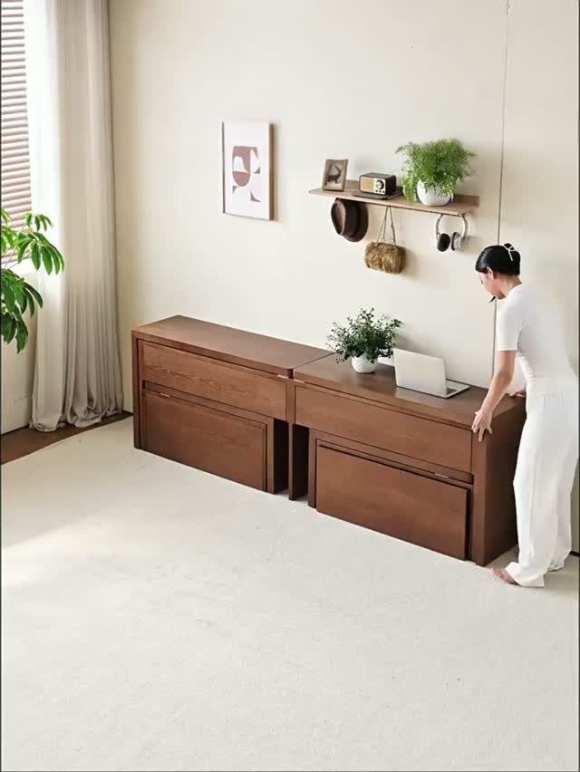 Woman standing by low brown wooden storage cabinets in a bright modern room.