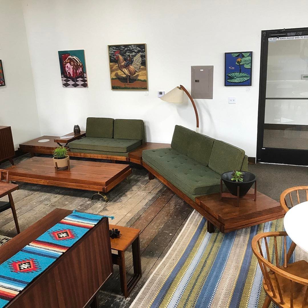 Olive green mid-century modern sofas with wooden frames in a bright living room.