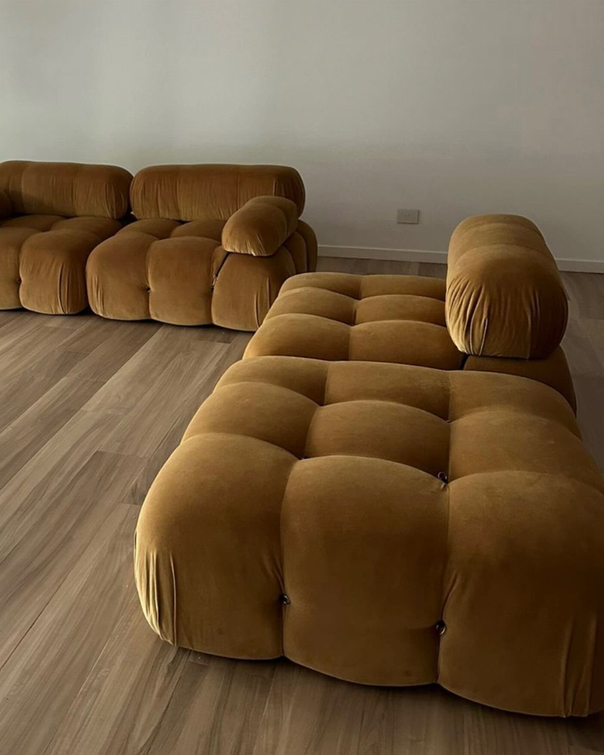 Mustard yellow modular tufted velvet sofas on a light wood floor.