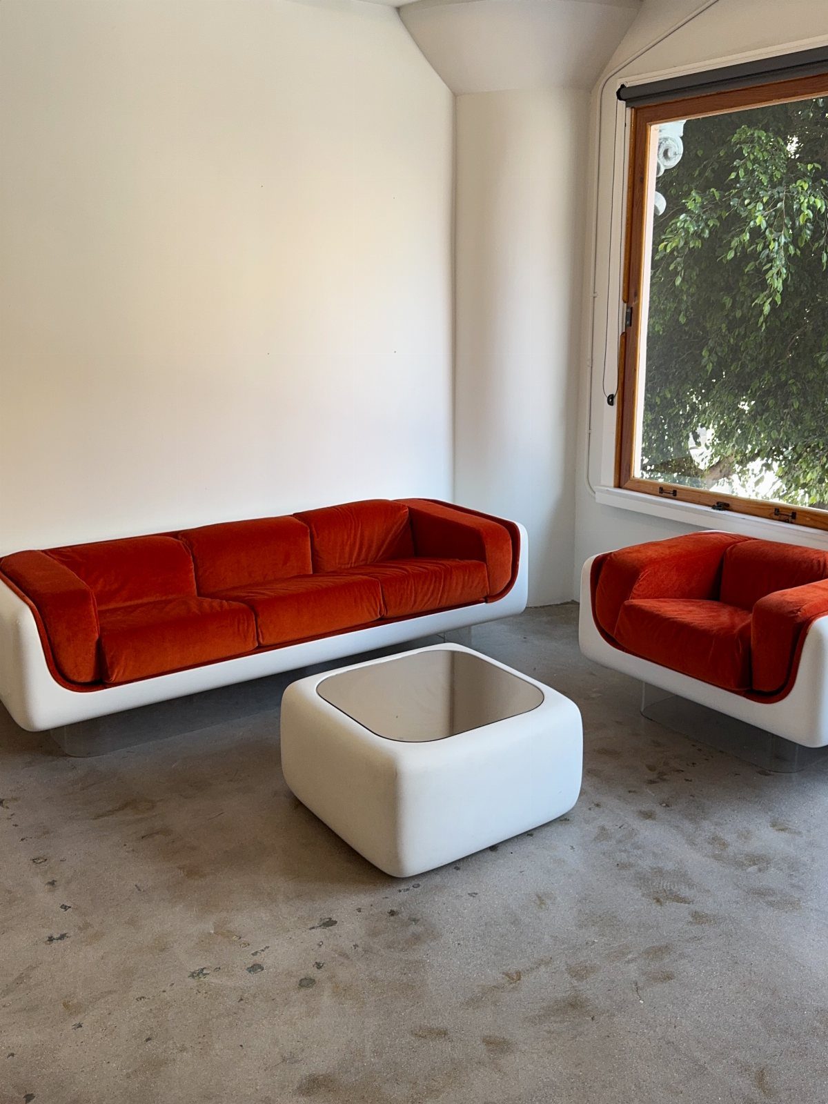 Orange velvet modern sofa and armchair with white frames in a minimalist room