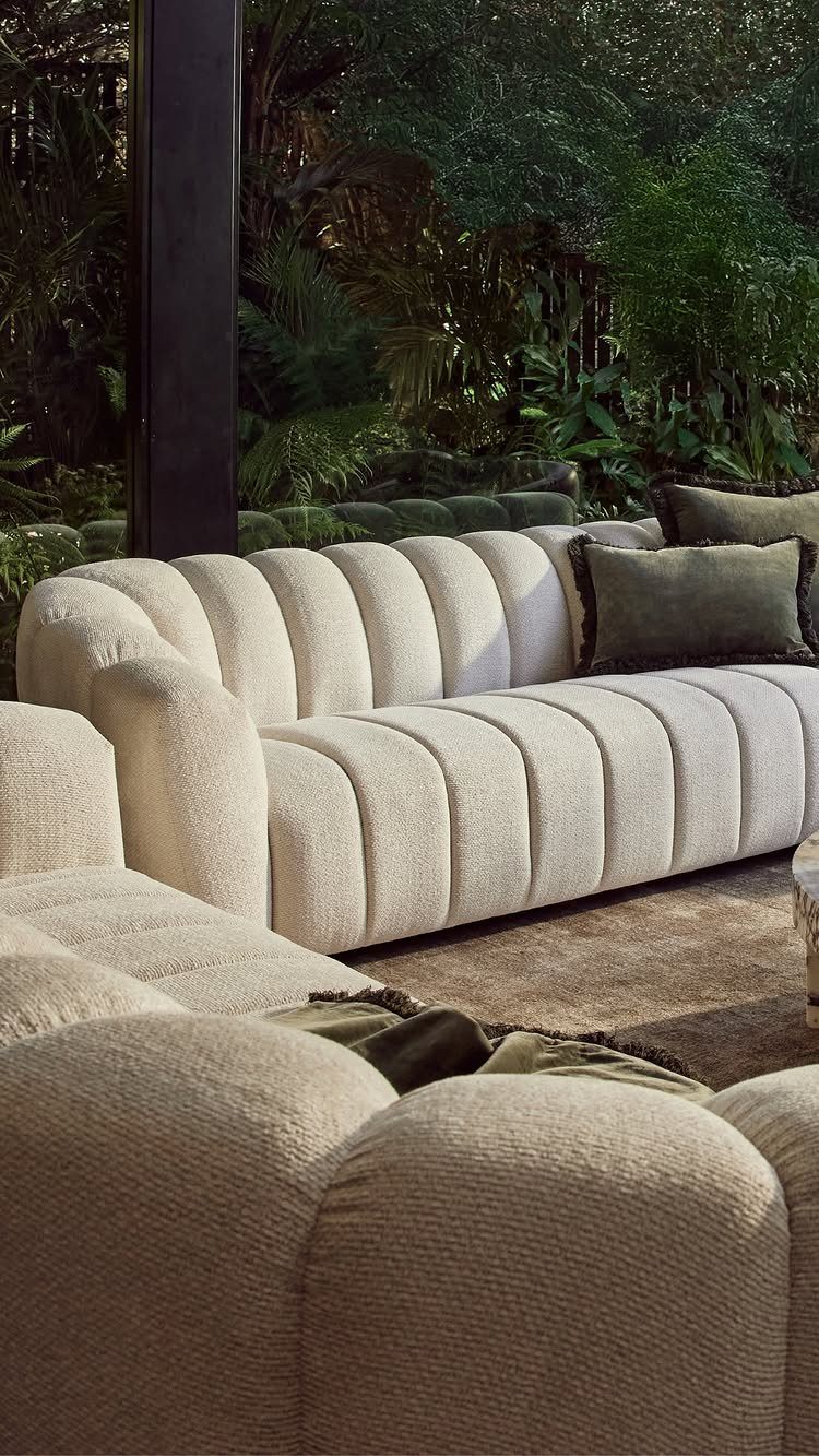 Cream ribbed modular sofa with green pillows in a modern living room setting