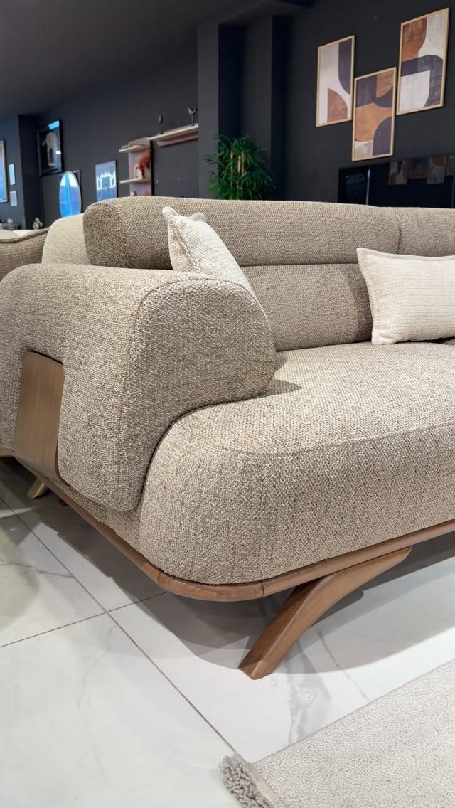 Beige fabric sofa with rounded arms and wooden legs in a modern room.