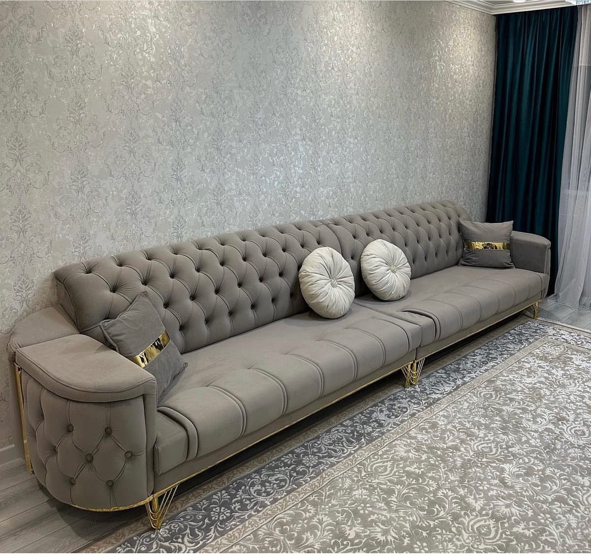 Grey tufted sofa with gold legs and decorative pillows in a modern living room