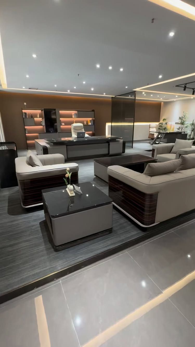 Modern office interior with a large desk and a beige couch seating area.