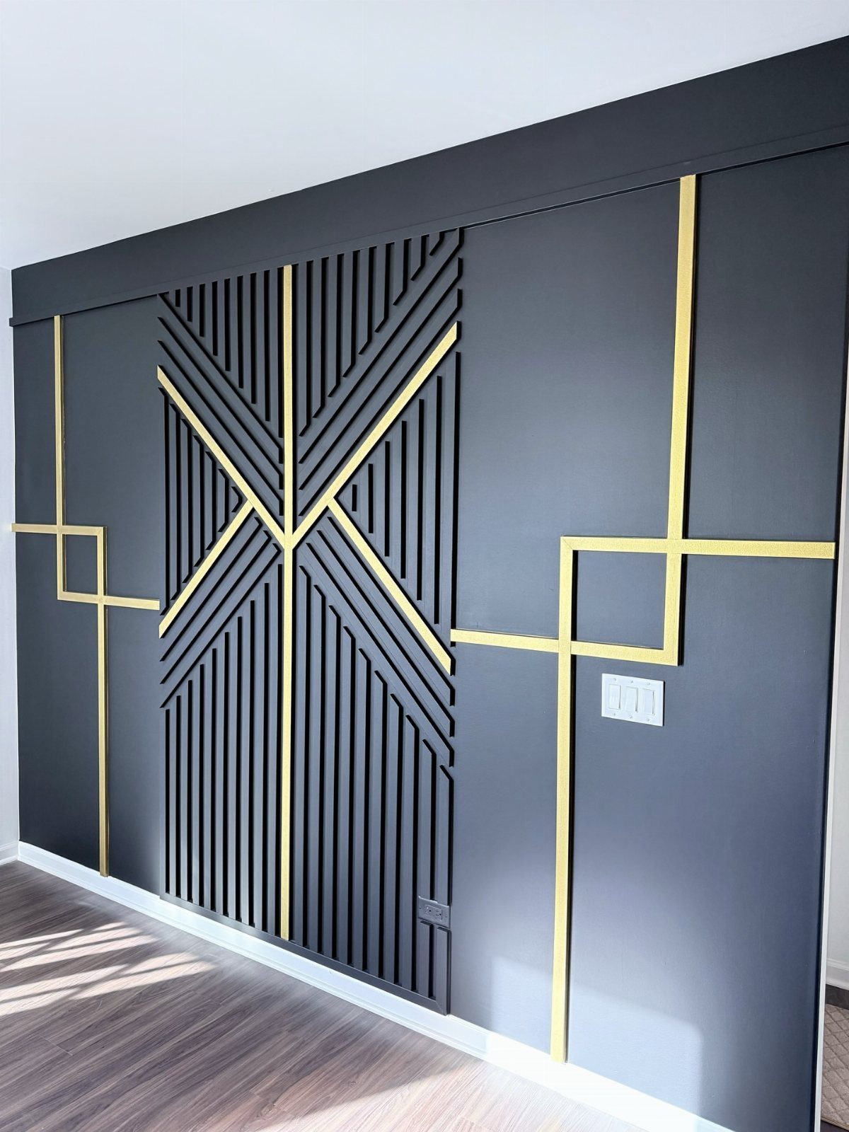 Black accent wall with gold geometric trim and vertical black wooden slats.