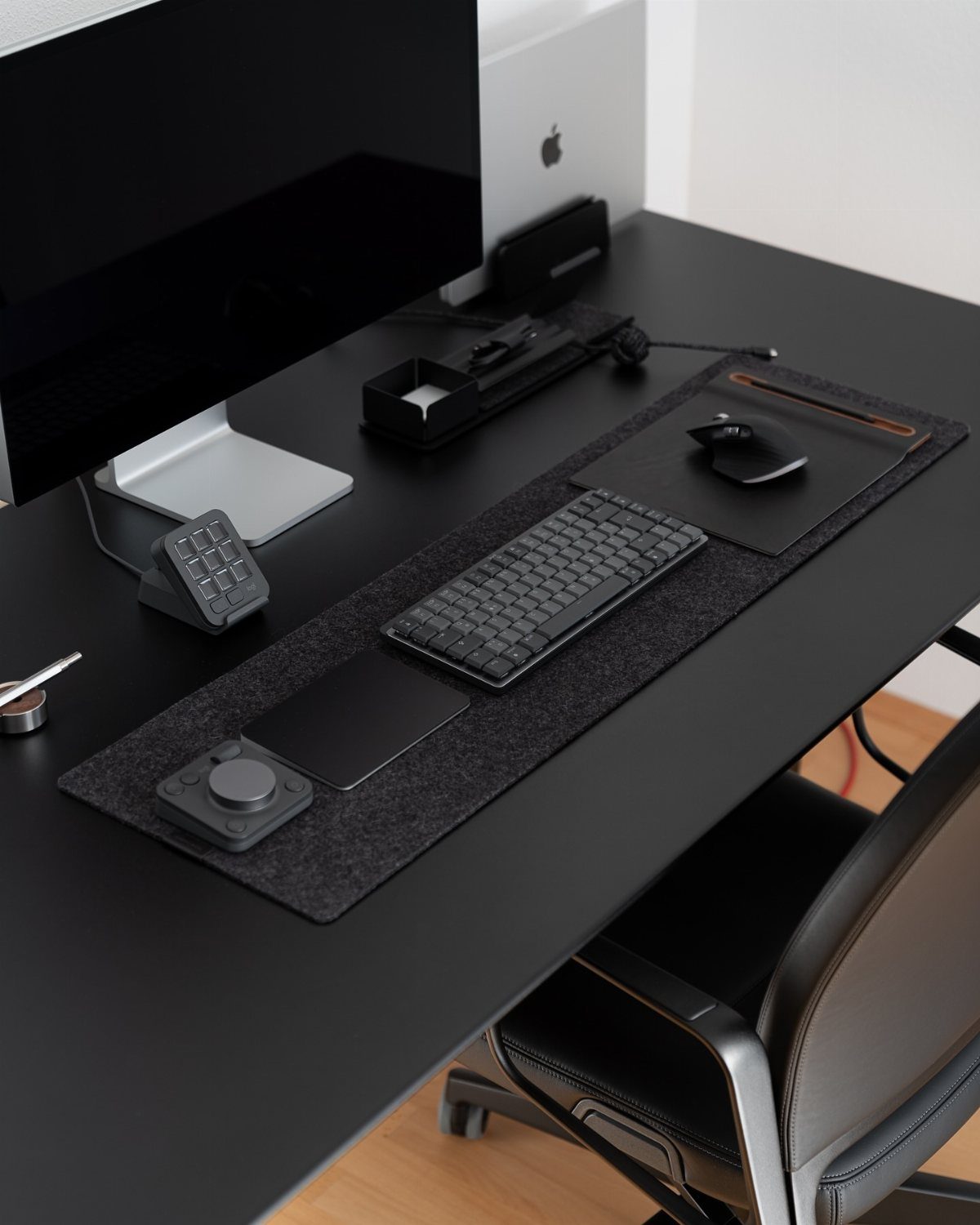 Black office desk with keyboard, mouse, and monitor in a modern workspace.