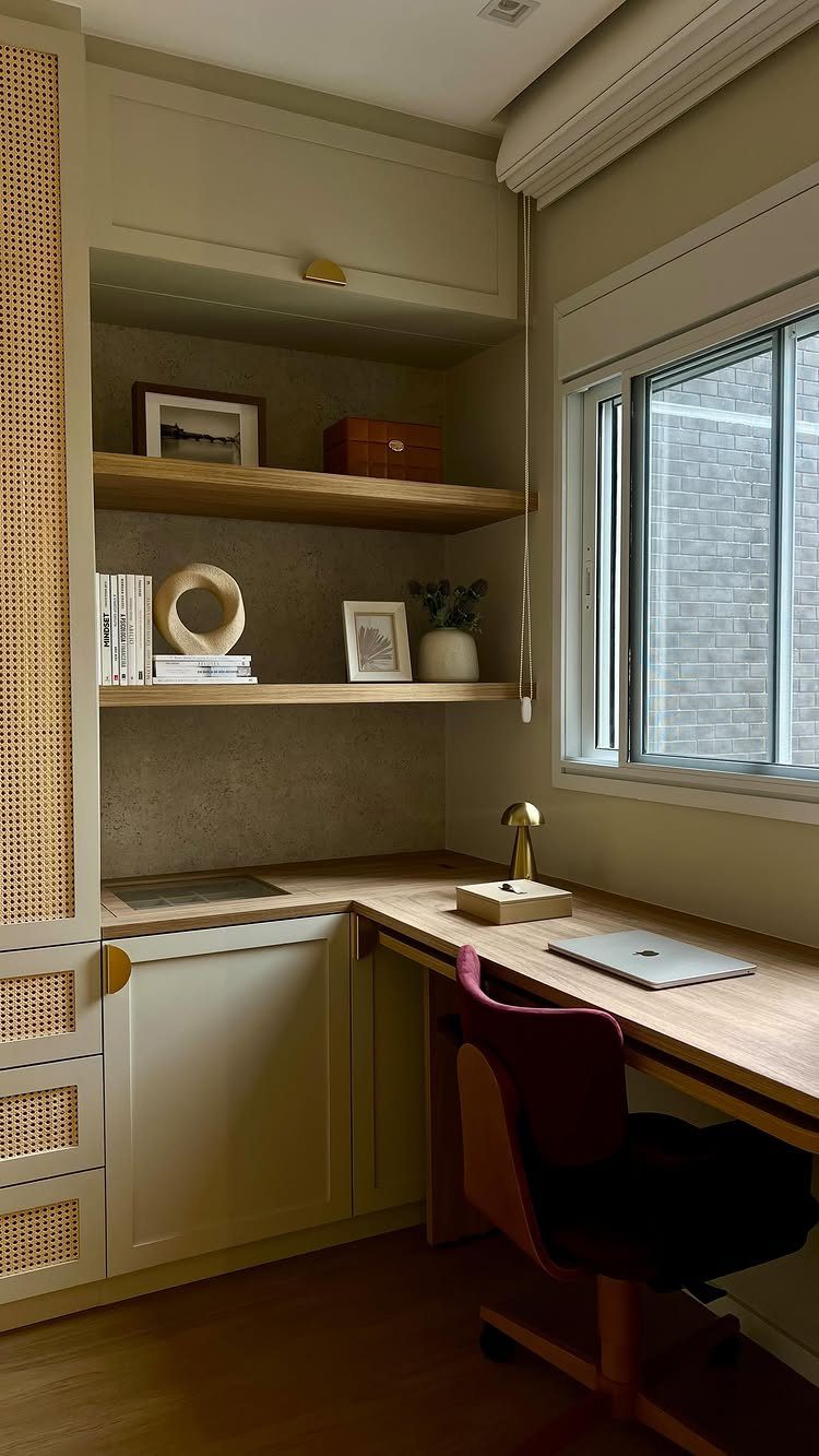 Built-in wooden desk in a recessed nook with floating shelves and maroon chair.