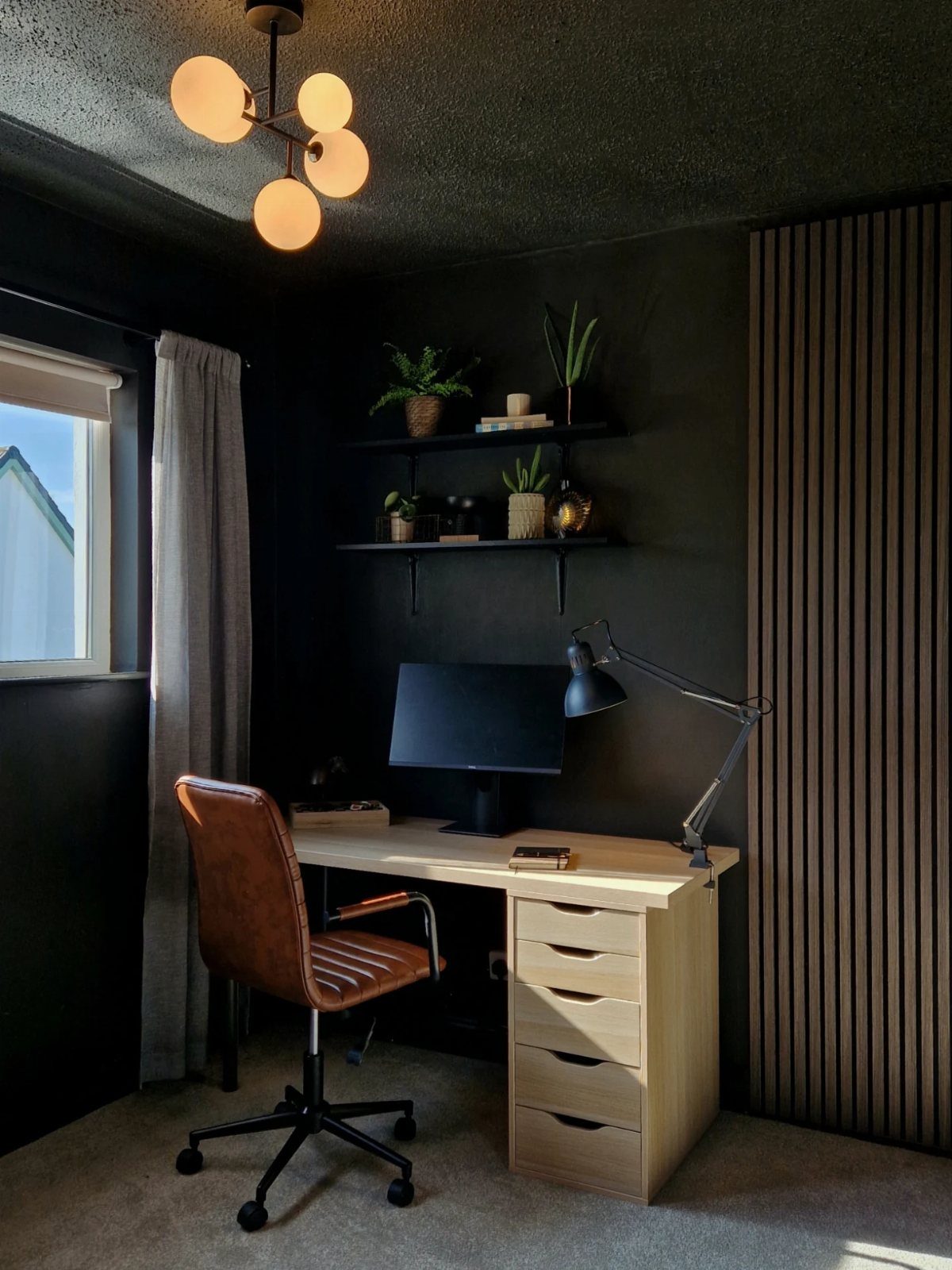 Light wood desk with brown leather chair against dark charcoal walls in office