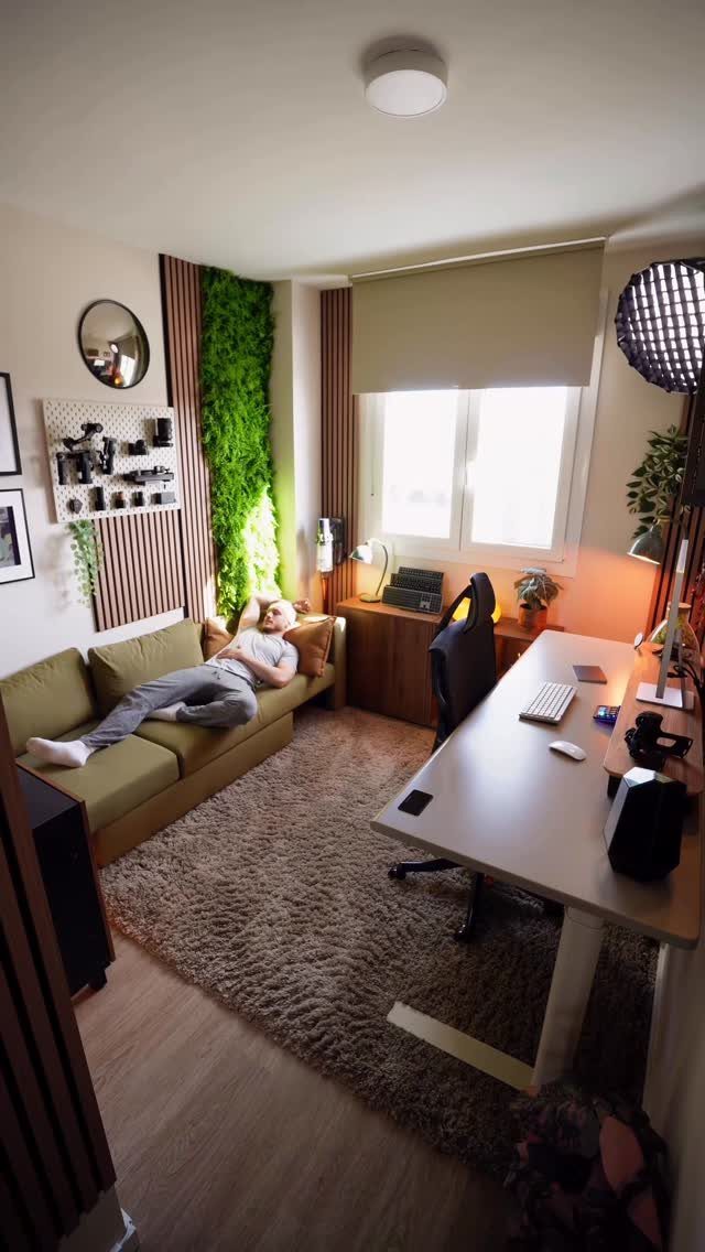 Man resting on a green sofa bed in a modern home office setup