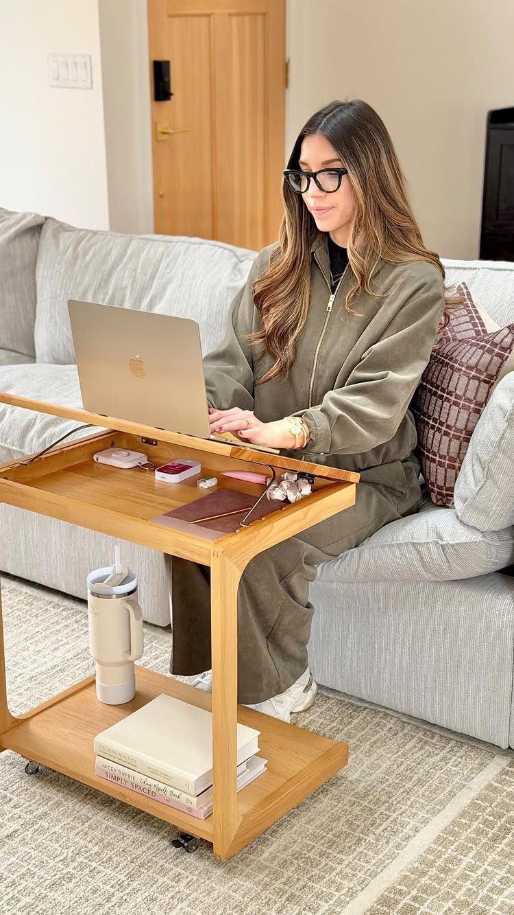 Woman working on a laptop using a wooden moveable side table by a sofa