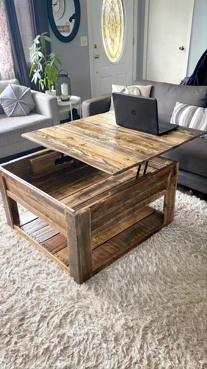 Pallet wood coffee table with a lift-top holding a laptop on a white rug.