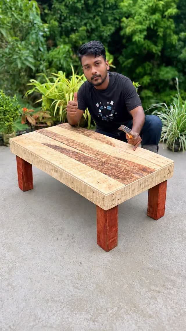 Pallet wood coffee table with a man posing behind it in a garden.