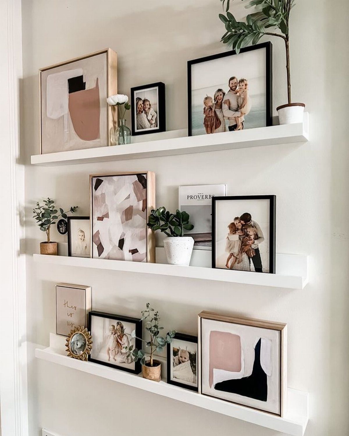 White picture ledges holding framed art and photos on a neutral wall