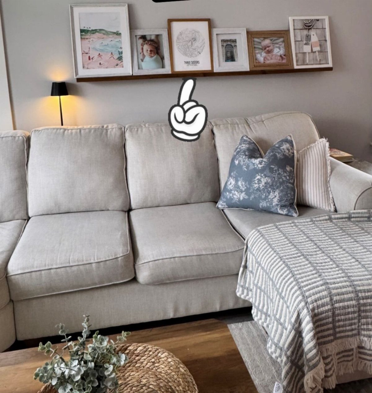 Wooden picture ledge with framed photos mounted on a wall above a grey couch