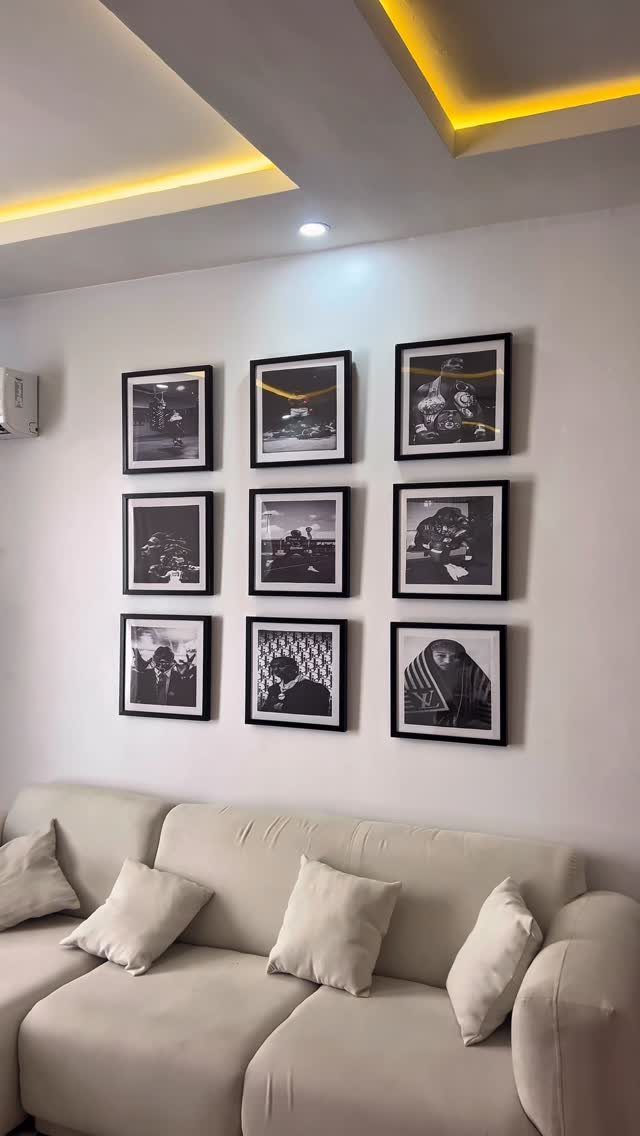 Nine black and white framed photos in a grid above a white sofa