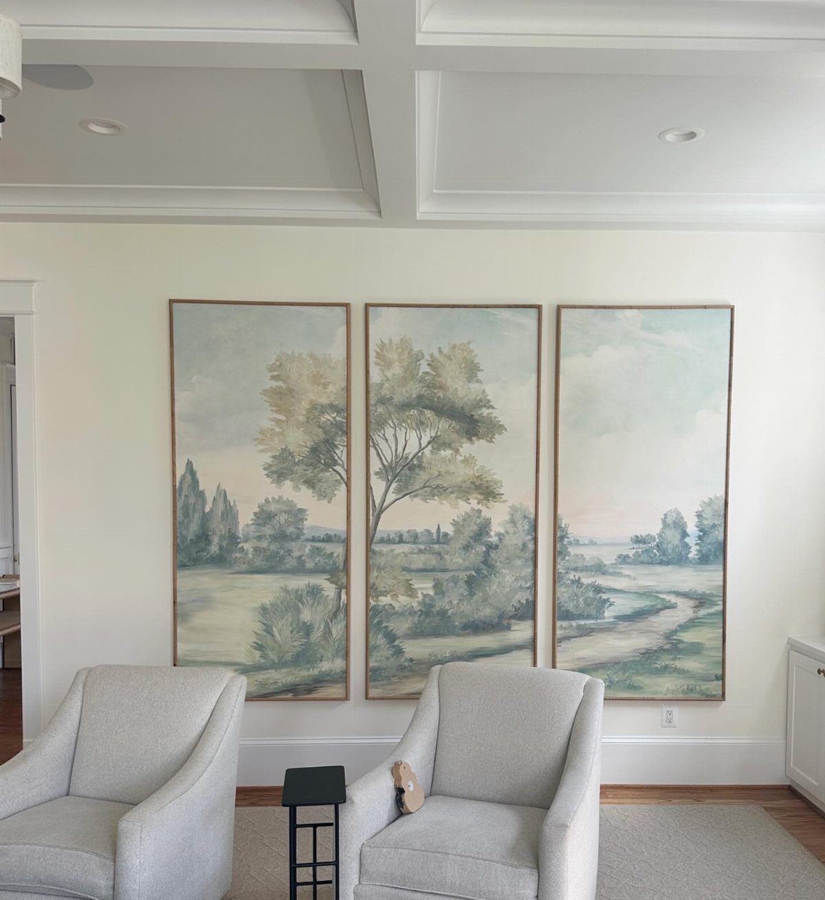 Three vertical landscape paintings arranged side-by-side on a white living room wall.
