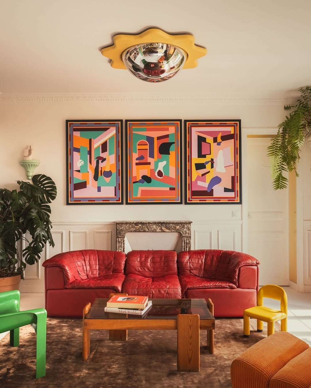 Red leather sofa in a living room with abstract art and colorful furniture.