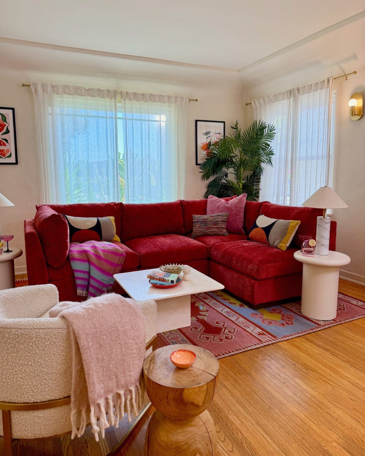 Red sectional couch in a bright living room with a patterned red rug.