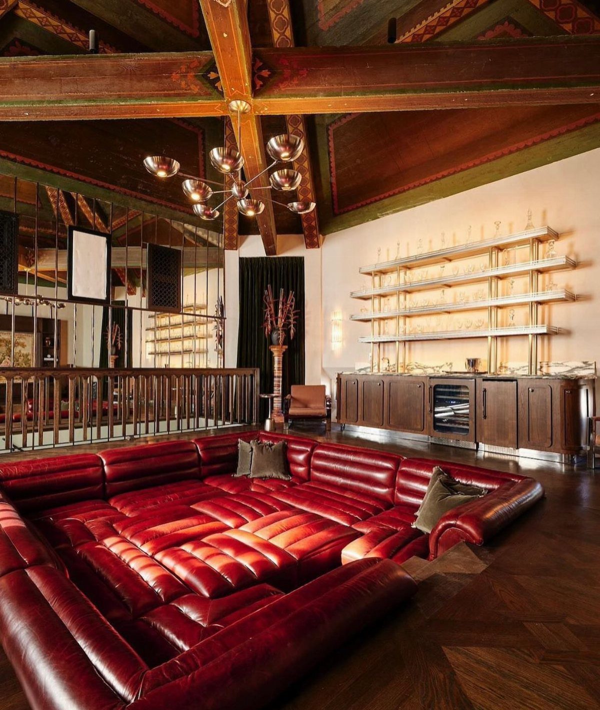 Sunken conversation pit with red leather upholstery in a room with wooden beams.